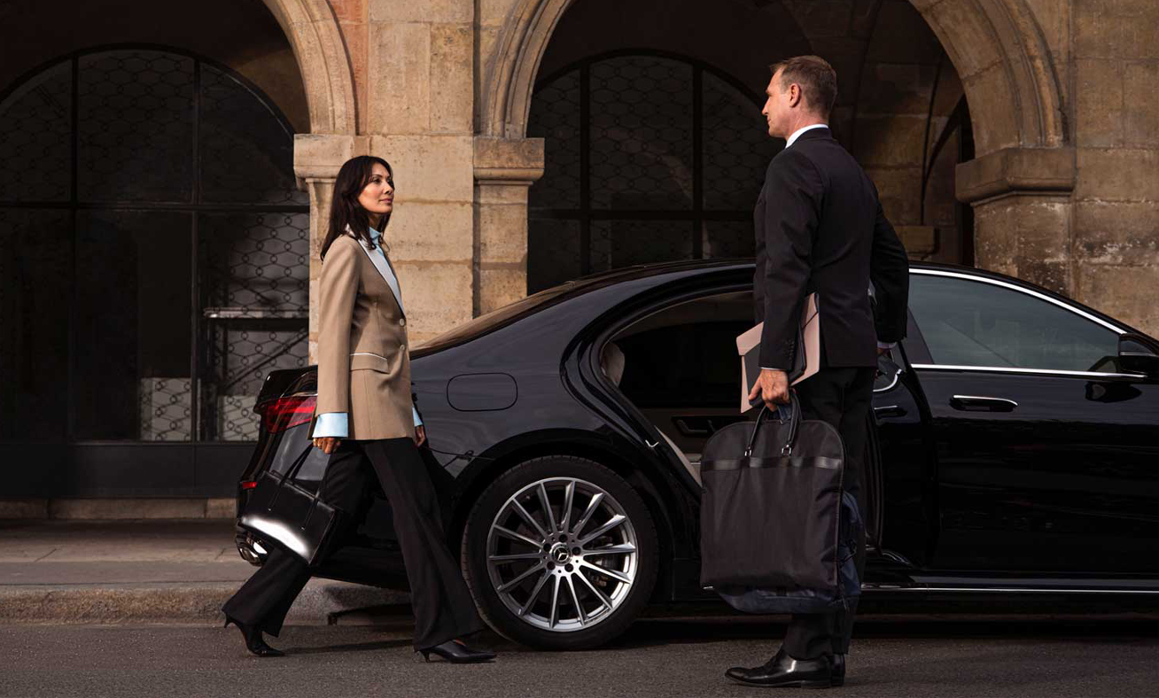 business woman move towards the luxury limo and chauffeur opens door of luxury limo for her